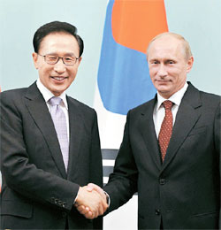 李明博大統領が９日、ブラジミール・プーチンロシア首相と会談に先立って握手をしている。