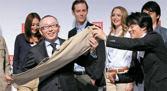 柳井正ユニクロ会長が東京で開かれた新商品発表会でズボンを手に持って見せている。