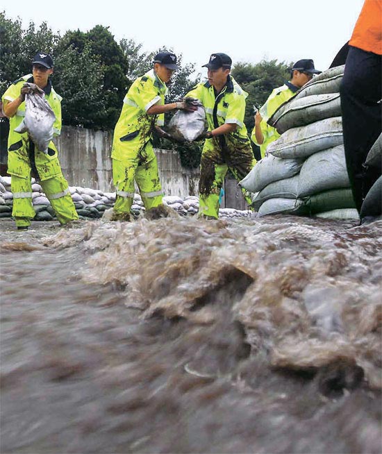 ソウル・牛眠洞（ウミョンドン）で３１日午後に豪雨が降り、１次復旧作業を終え撤収した警察兵力が再出動して住宅街に押し寄せる雨水を防ぐための土のうを積んでいる。