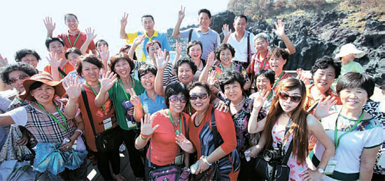 １４日、済州道西帰浦市の柱状節理帯を訪れた中国宝健日用品有限公司の職員が記念撮影している。 同社の職員１万１０００人は２４日まで８グループに分かれて済州道を訪問し、観光を楽しむ。