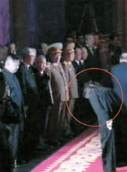 丸の中は、２１日に錦繻山（クムスサン）記念宮殿で、金オクが金正日の遺体を参拝した後、金正恩に深く頭を下げる姿（写真＝朝鮮中央テレビ）。