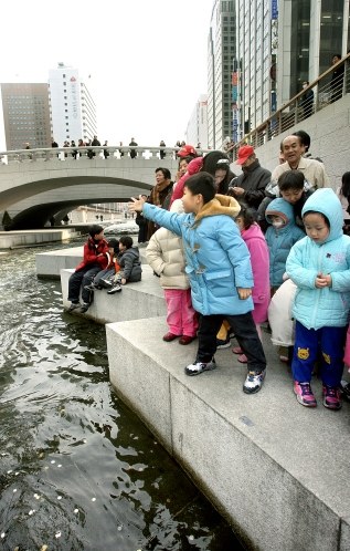 園児が願掛けをしながら清渓川（チョンゲチョン）に硬貨を投げ入れている。