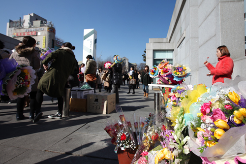そう、今日は人生の門出を祝う卒業式！正門前には卒業生に贈る色鮮やかな花束が売られ、会場に華やかな色を添えます。