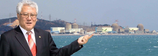 キム・スグン釜山（プサン）市議員が１５日、釜山市機張郡（キジャングン）の海辺で、古里（コリ）原発事故防止対策について話している。後ろに古里原発１号機が見える。 