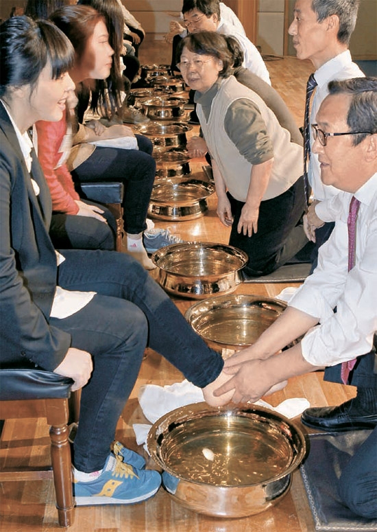 「洗足式」で教授らが学生の足を洗っている。