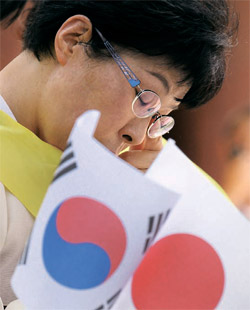 １４日、ソウル・タプコル公園の前で「韓日の歴史を克服し友好を推進する会」のメンバーが日本軍慰安婦問題に謝罪を促す集会の途中で涙を流している。