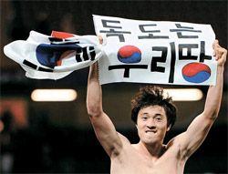 韓国の五輪サッカー３位が決まった後、「独島はわれわれの領土」と書かれた紙を持ってパフォーマンスをした朴種佑（パク・ジョンウ）（写真＝中央フォト）。