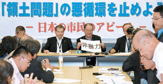 日本の知識人と市民団体代表が２８日、東京の参議院議員会館で記者会見を行い、「非暴力」と書かれた紙を見せている。