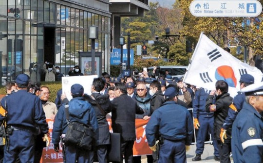 島根県が主催した「竹島の日」行事が開かれた２２日、行事場所の島根県民会館の外で、独島守護全国連帯など韓国市民団体会員が日本の警察に囲まれながら太極旗を持って抗議デモを行っている。