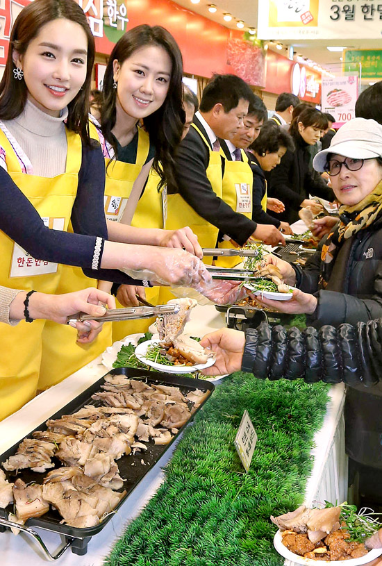 ４日、ソウル 良才洞（ヤンジェドン）の農協流通の店舗の試食イベント会場で、２０１２年ミスコリアの善（２位に相当）のイ・ジョンビンさん（右）と真（１位に相当）のキム・ユミさんが市民にサムギョプサルを配っている。