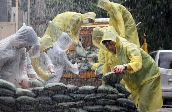 １３日、ソウル良才洞（ヤンジェドン）の住宅街で集中豪雨対策訓練が行われ、瑞草（ソチョ）区庁の災難治水課職員が浸水を防ぐために砂袋を積んでいる。