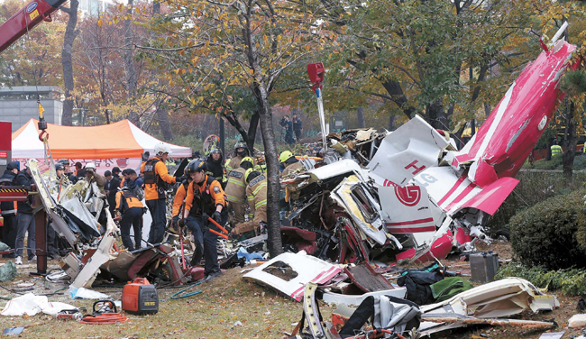 マンションに衝突し墜落したヘリコプターの残骸を検分する消防。