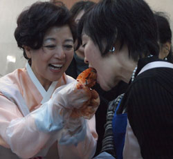 安倍昭恵さん（右）が大使夫人の沈載令さんが渡したキムチを試食している。（写真＝駐日韓国大使館）