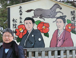 「松陰神社」入口の看板。吉田松陰と弟子である前原一誠の顔の絵。その前に立つ筆者パク・ポギュン論説委員。