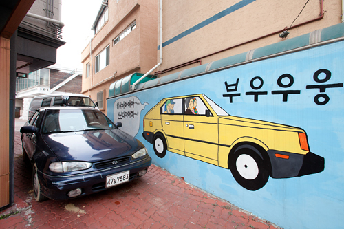 駐車スペースの壁には、鮮やかな黄色の車。本物と比較してみれば、その大きさが一目で分かります。