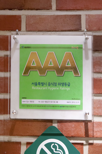 そうしたなかソウル市が、消費者保護と事業者間の競争を促すため２００９年に始めたのが「飲食店衛生等級制」。飲食店の衛生状態をトイレ衛生度など４分野４４項目で検査し、評価点数により等級表示板を配布する制度（２年に１度再検査、Ａの数が多いほど高得点）です。