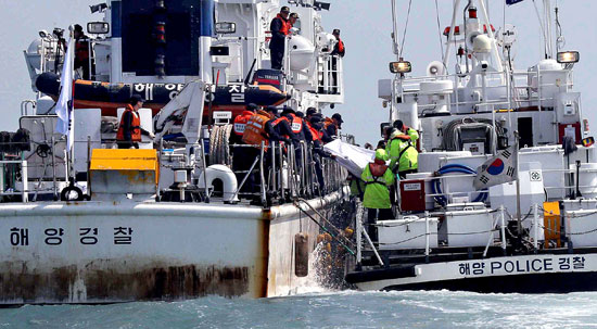 海洋警察の隊員が２０日午後、「セウォル号」沈没事故海域の海上で遺体を収容している。官民軍合同救助チームの潜水要員は１９日午後、初めて船体のガラス窓を割り、船内に入って３人の遺体を引き揚げた。救助チームが遺体を珍島パンモク港に運ぶ船に移している。