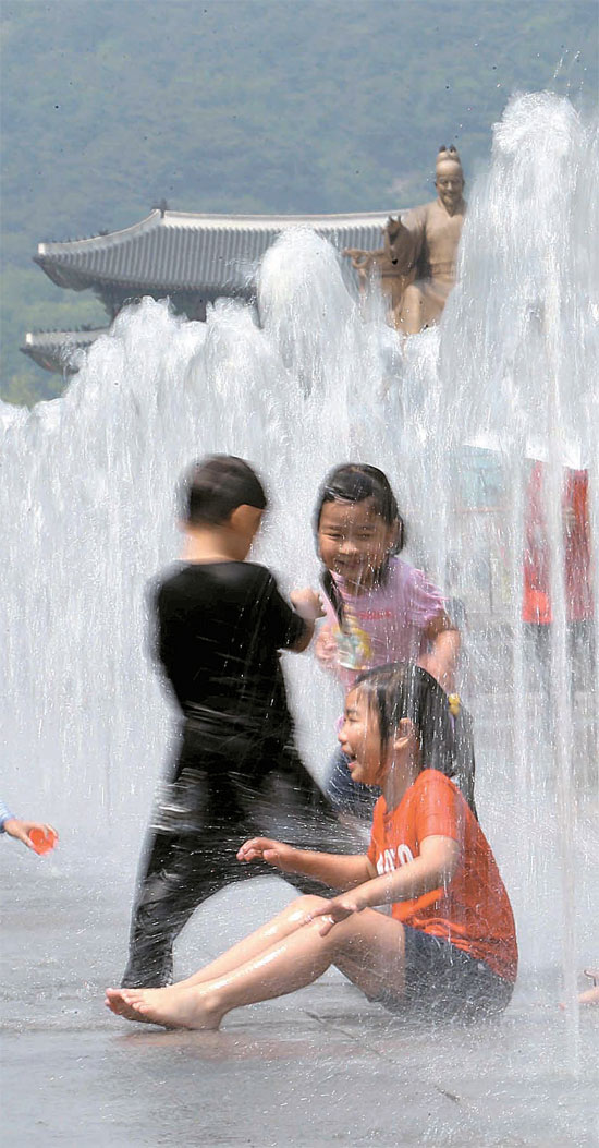 １８日、ソウル光化門（クァンファムン）広場の噴水台で水遊びをしている子供たち。