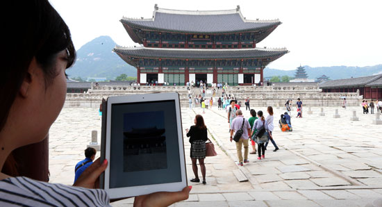 ある観光客が拡張現実（ＡＲ）基盤で作られた「私の手の中の景福宮（キョンボックン）」アプリを起動して、勤政（クンジョン）殿についての映像と説明を聞いている。