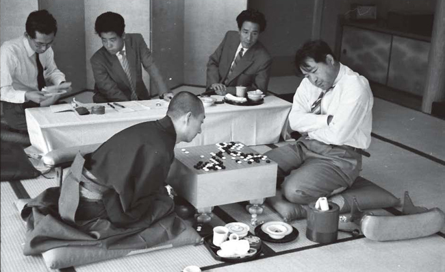 １９５０年代末、呉清源（左）と藤沢庫之助の対局。盤上ではマネ碁が繰り広げられている。対局者の中央に見える棋士は坂田。宗教的な品性が強かった呉清源はいつも断髪姿だった。（写真＝日本棋院）