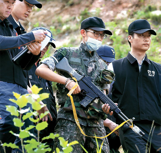 ８日、事件現場でＫ－２小銃を持って当時の状況を再演しているイム兵長。（中央、写真＝共同取材団）