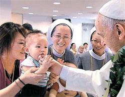 同日、法王が陰城の福祉施設「コットンネ」である赤ん坊の口に自身の指を近づけて笑顔を見せている。（写真＝共同取材団）