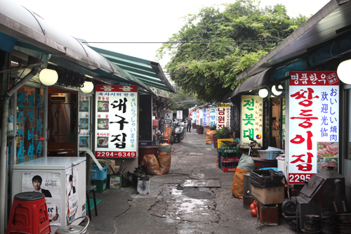 市場を通り抜けると「焼肉横丁」に到着。ディープな雰囲気が漂うこの通りには、開業３０年以上の老舗を含む約３０店舗の牛専門の焼肉店がずらりと立ち並びます。店名に「大邱（テグ）」や「南原（ナムォン）」など地域名が多いのは、店主の故郷からとっているからだそう。
