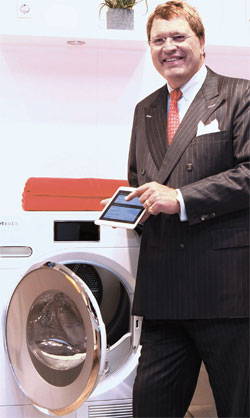 ５日にドイツで開かれた家電見本市ＩＦＡ２０１４に参加したミーレのラインハルト・ジンカン会長がタブレットＰＣでドラム洗濯機を作動させている。創立１１５年を迎えたミーレはスマートホームである「ミーレアットホーム」を初めて公開した。（写真＝ミーレ）