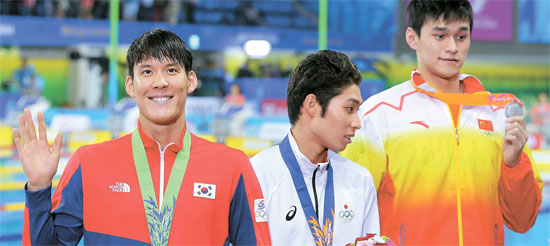 朴泰桓（１８３センチ、左）が仁川アジア競技大会自由形男子２００メートルの表彰式の後、観客に手を振っている。１位は日本の萩野公介（１７５センチ、真ん中）、２位は中国の孫楊（１９８センチ）で、朴泰桓は３位だった。