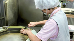 日本の包丁メーカー貝印の工場で従業員が製造工程最後の段階で砥石で包丁を研いでいる。