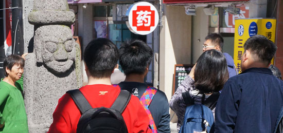 済州島で中国人観光客が最も多く集まる所に挙げられる済州市蓮洞の宝健通り。中国語の簡体字が書かれた看板を掲げた店のそばに済州の象徴であるトルハルバンが並んでいる。