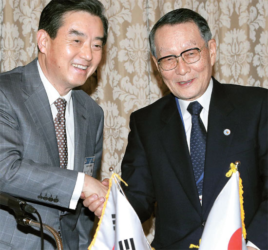 １４日、ソウル小公洞のロッテホテルで開かれた韓日経済人会議で共同声明書を採択した後、両国代表のキム・ユン韓日経済協会会長（左）と佐々木幹夫日韓経済協会会長が握手している。