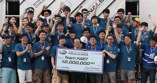 ６日に米防衛高等研究計画局（ＤＡＲＰＡ）ロボット大会で優勝したＫＡＩＳＴチームのオ・ジュンホ教授（前列中央のめがねの人物）とチーム員が賞金を手に歓呼している。（写真＝ＫＡＩＳＴ・ＤＡＲＰＡ）