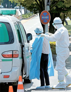 １０日午後、救急車でサムスンソウル病院に到着した患者が医療スタッフの助けを受けて防護服を着ている。この日午前現在の中東呼吸器症候群（ＭＥＲＳ）確診患者は１３人増えて計１０８人になった。