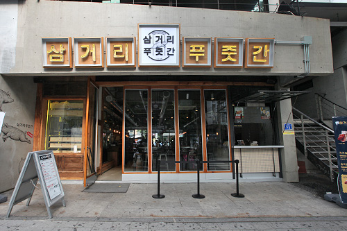 芸能人経営のグルメ店が多い弘大（ホンデ）。韓国大手芸能事務所ＹＧエンターテイメントのヤン社長は居酒屋｢サムゴリポチャ｣などの経営で有名ですが、最近ＹＧ　ＦＯＯＤＳを設立し本格的に外食産業へ参入。豚焼肉専門店｢サムゴリ プジュッカン｣をオープンしました。