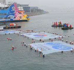 蔚山から独島まで水泳大長征に出た選手が大型太極旗を広げている。（写真＝蔚山南区庁）