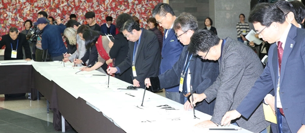 ２２日、済州道西帰浦市中文洞の済州国際コンベンションセンター（ＩＣＣ済州）で開かれた「アート＆アジア済州２０１５」の開幕行事の様子。韓日中３カ国から参加した４８人の関係者が同時に筆文字を書くパフォーマンスが行われた。（写真＝済州道）