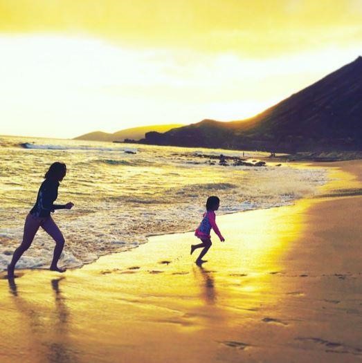 夕焼けを背景に浜辺を走っているＳＨＩＨＯと娘のチュ・サランちゃんの様子。（写真＝ＳＨＩＨＯのインスタグラム）