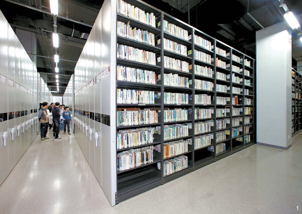 （１）１４日、見学参加者が職員の説明を聞いて地下書庫を見学している。