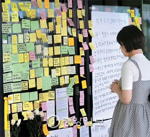 先月３１日、ソウルの地下鉄九宜駅のプラットホームである女性がスクリーンドアに貼ってあるメッセージを見て追悼している。