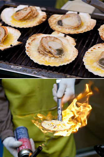 ホタテから出た旨みたっぷりのエキスの上に、チーズをたっぷりかけたホタテのチーズ焼き（カリビクイ、８，０００ウォン）は、最後に貝殻ごと焼き上げるファイヤーショーで道行く人の目を奪います。