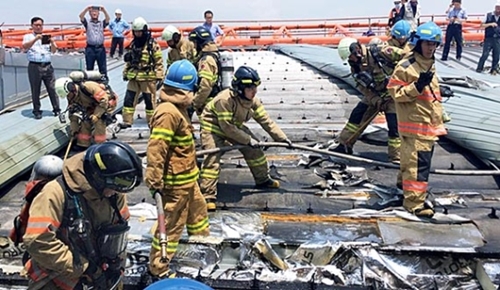 １１日午後、リフォーム工事中だったソウル金浦空港国内線庁舎３階屋上の遮光幕から火災が発生した。消防隊員が消火活動を行っている。〔写真＝江西（カンソ）消防署〕