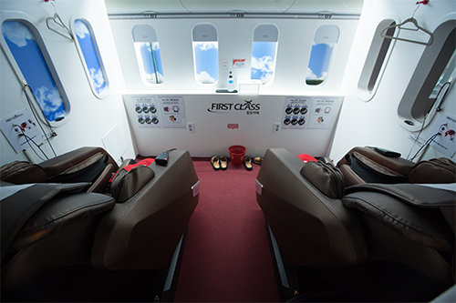飛行機をイメージしたカフェ「ＦＩＲＳＴ　ＣＬＡＳＳ」には、コーヒーやワッフルと全身マッサージを楽しめるプランが完備。世界各国の都市名が書かれた個室では、まるで飛行機のファーストクラスで空の旅を楽しんでいるかのような気分を味わえる演出も。