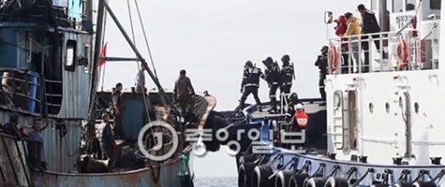群山海警特攻隊員（右）が先月３０日、韓国側の排他的経済水域（ＥＥＺ）の群山市於青島（オチョンド）沖で違法操業をした中国漁船に乗り込んでいる。海警は２９－３０日、中国漁船７隻を拿捕した。