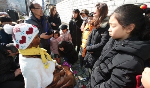 ことし１月、市民が家族単位で釜山東区庁日本領事館前に設置された少女像を訪れて記念撮影をしている。