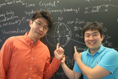 チェ・ジュンヒさん（左側）・チェ・スンウォンさんがタイム・クリスタルに関する数学公式や原理などを書いた黒板の前でポーズを取っている。