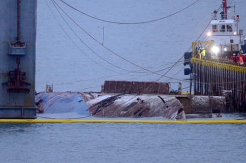 ２３日午前、セウォル号沈没海域である全羅南道珍島郡の東巨次島（トンゴチャド）沖で、中国引揚げ企業「上海サルベージ」のジャッキングパージ船２隻がセウォル号の引き揚げ作業を進めている中、セウォル号が姿を表わしている。（写真＝珍島＝写真共同取材団）