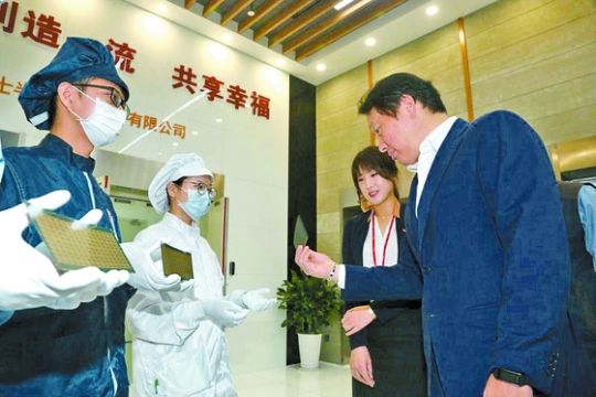 崔泰源ＳＫグループ会長（右）が昨年９月ハイニックス中国重慶工場で半導体製品をチェックしている。崔会長はハイニックスに強い愛着を見せた。（写真＝ＳＫグループ）