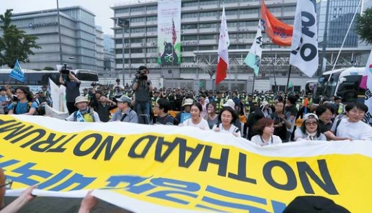 ２４日午後にソウル広場で開かれた「ＴＨＡＡＤ撤回平和行動集会」の参加者が駐韓米国大使館前で「ＴＨＡＡＤ強要米国糾弾、ＮＯ　ＴＨＡＡＤ　ＮＯ　ＴＲＵＭＰ」と書いた垂れ幕を持ってスローガンを叫んでいる。２０００人余りの参加者は１９分間にわたり大使館を囲みデモを行った。