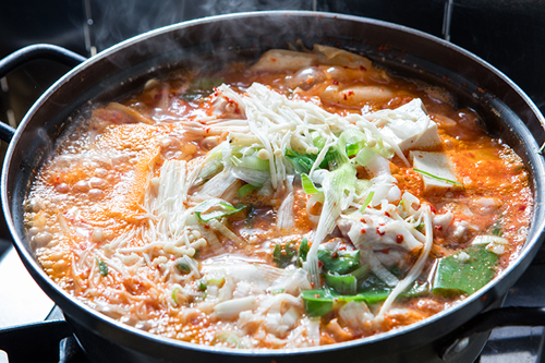韓国の夏バテを防止する方法　「以熱治熱（イヨルチヨル、熱を以って熱を治す）」。「キムチチゲ」は、韓国料理の中でも１、２位を争う定番メニュー。キムチと豆腐やネギ、豚肉などを煮込んでおり、ちょっぴり酸味の効いたスープが食欲をそそります。豚肉の他に、ツナ入りやサンマ入りなど、バラエティーも豊富です。